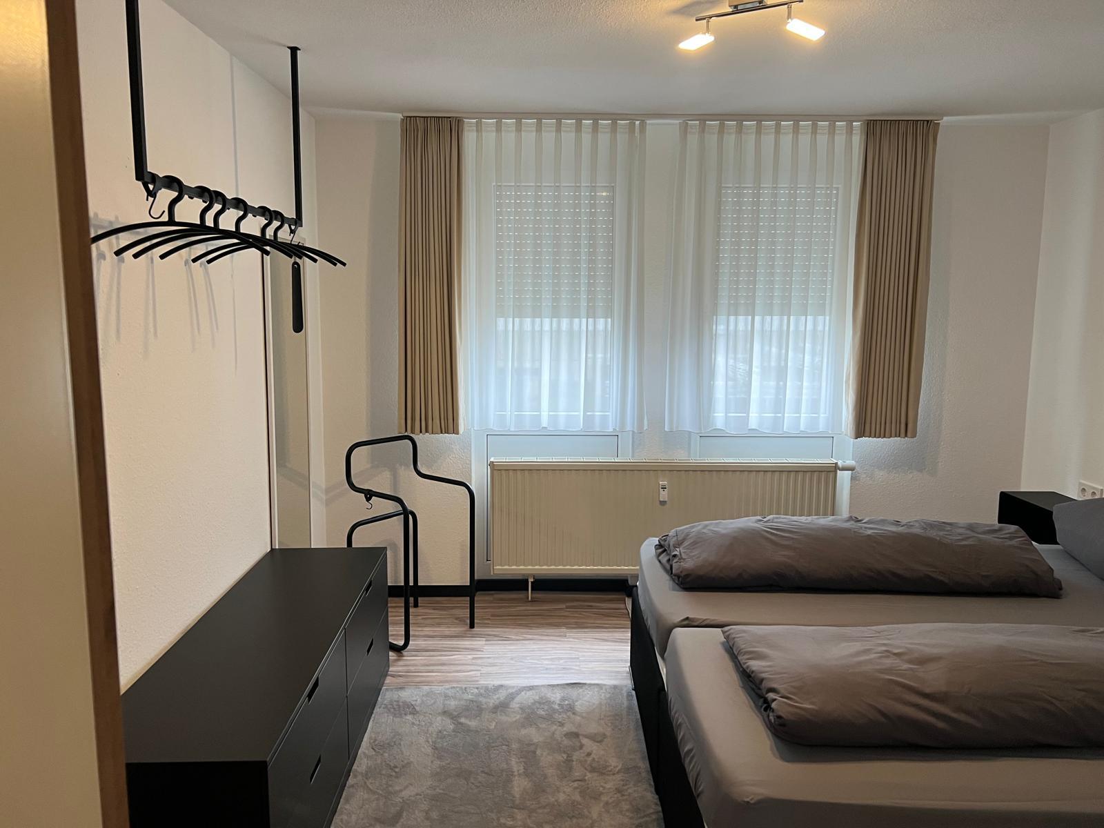 Schlafzimmer mit Kommode, Garderobe und Fenstern
